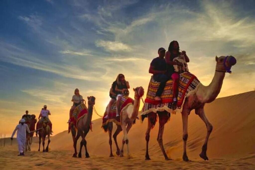 A clear night sky full of stars above the golden sand dunes in the Dubai desert, with a group of people enjoying a stargazing experience.